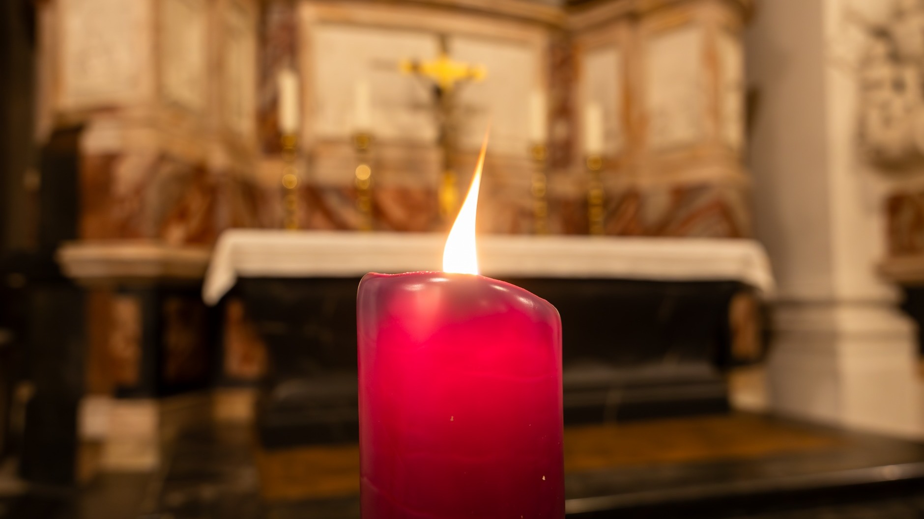 Im Fuldaer Dom brennt das Friedenslicht aus Bethlehem als rote Kerze vor einem Seitenaltar. Für Fuldas Bischof Dr. Michael Gerber ist die kleine Flamme auch angesichts der aktuellen Kriege und Krisen in der Welt ein Hoffnungszeichen. Foto: Bistum Fulda / Burkhard Beintken